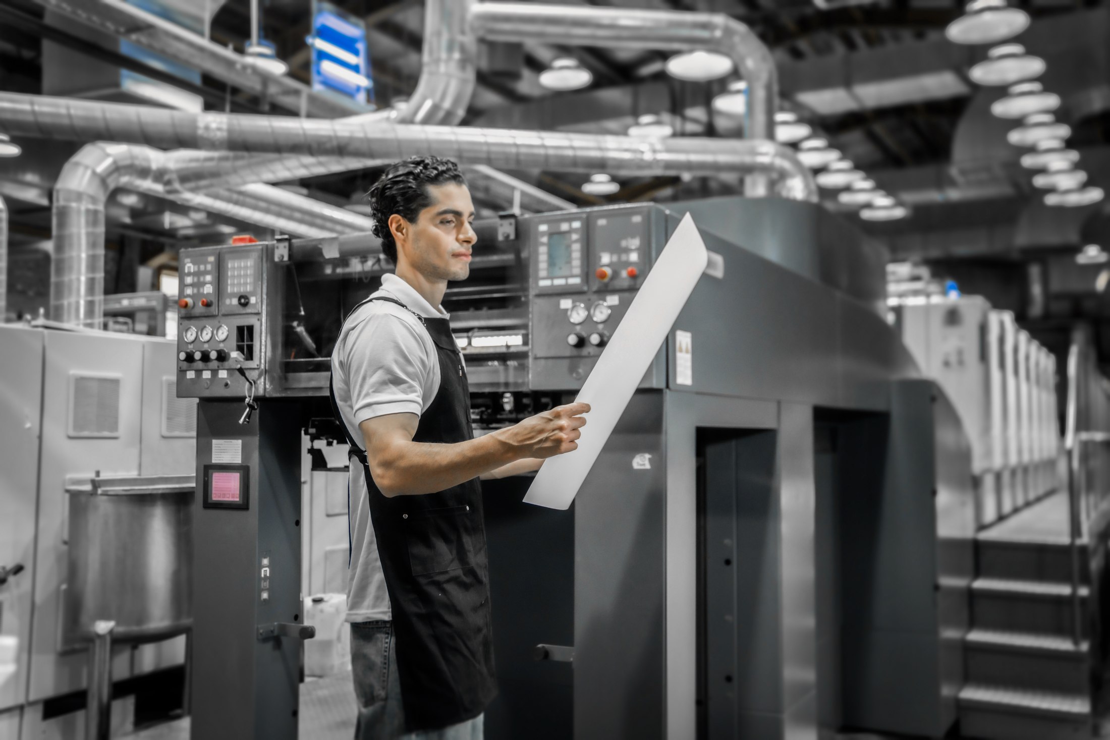 Offset press operator inspecting a sheet